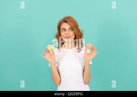 sorridente ragazza tenere dolce macaron francese cookie su sfondo blu Foto Stock