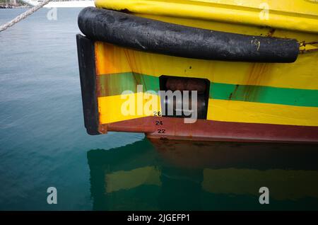 Prua di barca gialla con linea d'acqua, passacavo, ancoraggio rialzato, parafango in gomma e segni di pescaggio sulla prua della nave. Prua della nave da pesca in primo piano Foto Stock