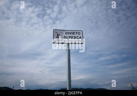 Piatto bianco contro cielo nuvoloso che dice Divieto di pesca significa pesca vietata in italiano. Cartello pesca vietata sul molo, la Spezia, Liguria Foto Stock