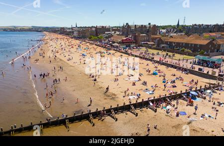 Portobello, Edimburgo, Scozia, Regno Unito. 10 luglio 2022. Una vista aerea di migliaia di amanti del sole sulla spiaggia di Portobello oggi con l'aumento delle temperature a 27C. La famosa spiaggia e il lungomare fuori Edimburgo sono stati a lungo un magnete per gli abitanti della città in estate. Iain Masterton/Alamy Live News Foto Stock