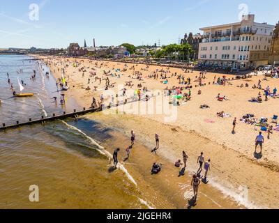 Portobello, Edimburgo, Scozia, Regno Unito. 10 luglio 2022. Una vista aerea di migliaia di amanti del sole sulla spiaggia di Portobello oggi con l'aumento delle temperature a 27C. La famosa spiaggia e il lungomare fuori Edimburgo sono stati a lungo un magnete per gli abitanti della città in estate. Iain Masterton/Alamy Live News Foto Stock