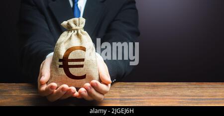 L'uomo d'affari tiene fuori la borsa di soldi dell'euro. Ipoteca, approvazione prestito. Denaro facile. Salario, prestazioni, profitto. Attirare investimenti. Risparmi sui depositi. Rimborso Foto Stock