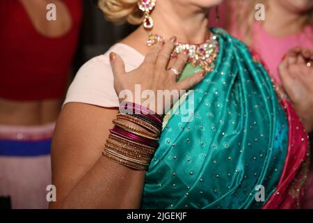 Collo e mani femminili con molti braccialetti boho, collana in pelle e orecchini con piume, turchese e marrone. Foto Stock