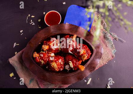 Pollo Szechuan, una ricetta popolare indocinese non vegetariana, servito in un piatto con salsa al peperoncino. Fuoco selettivo. Spazio per copie. Foto Stock