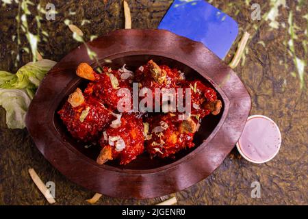 Pollo Szechuan, una ricetta popolare indocinese non vegetariana, servito in un piatto con salsa al peperoncino. Fuoco selettivo. Spazio per copie. Foto Stock
