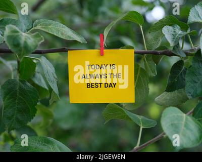 Una nota di carta con la frase oggi è sempre il giorno migliore su esso attaccato ad un albero con un perno di vestiti. Primo piano. Foto Stock