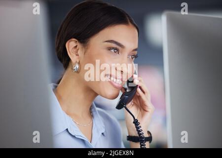 E' un piacere essere d'aiuto. Un giovane e attraente agente di call center seduto da solo in ufficio e con un telefono. Foto Stock