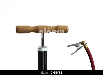 Pompa d'aria manuale d'epoca per biciclette, primo piano dell'impugnatura in legno e tubo flessibile rosso su sfondo bianco Foto Stock