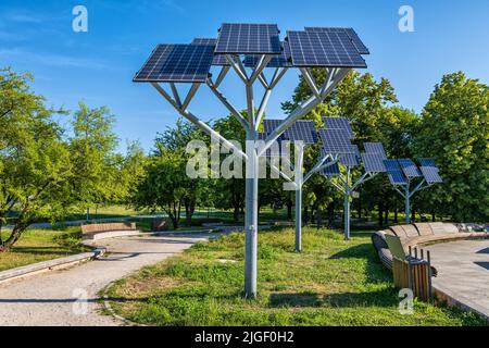 Pannelli solari su uno stand nel parco cittadino, moduli fotovoltaici, fonti di energia rinnovabile sostenibili. Foto Stock