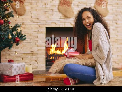 Un po 'di qualcosa per battere le calze di Natale fuori. Una giovane donna felice di apertura presenta durante il Natale a casa. Foto Stock