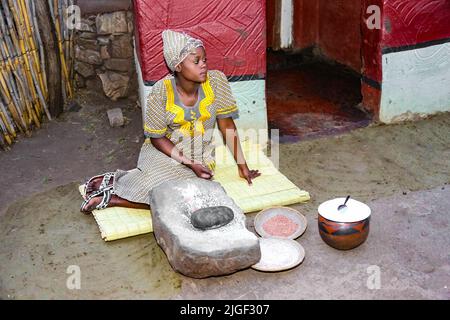 Johannesburg, Sudafrica - 18 settembre 2013: Donna africana fuori casa tradizionale con macinatura pietra Foto Stock