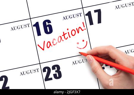 16th agosto. Una mano che scrive un testo DI VACANZA e che disegna un volto sorridente su una data di calendario 16 agosto. Concetto di pianificazione delle vacanze. Mese estivo, d Foto Stock