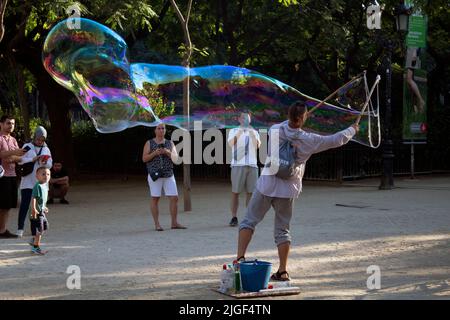 Uomo che crea bolle giganti con una bacchetta gigantesca nella Plaza de la Sagrada Família, Barcellona, Catalunya, Spagna Foto Stock