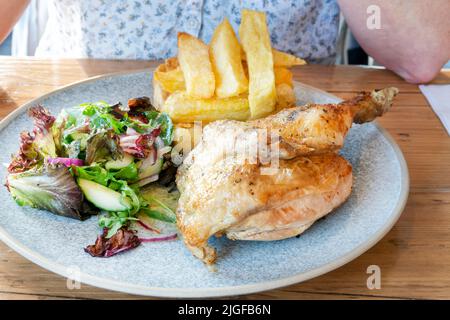 Un tradizionale pasto britannico half roast chicken pub. La carne è stata servita al tavolo con una pila di patatine cotte triple e un'insalata mista. Foto Stock