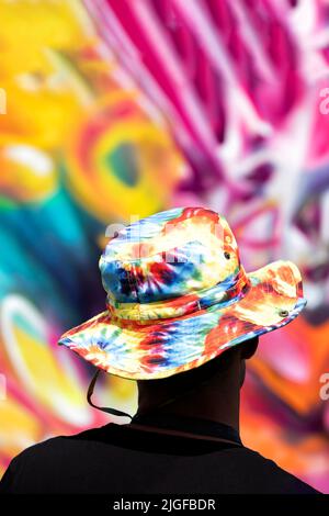 Bristol, Regno Unito. 28th maggio 2022. Un artista di strada che indossa un colorato cappello tinto legato si erge indietro per accedere alla sua opera d'arte durante il Bristol Upfest, 2022, fest Foto Stock