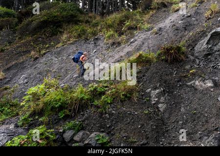 WA20558-00....WASHINGTON - Backpacker attraversando una testa di spiaggia fangosa con l'aiuto di una corda nel Parco Nazionale Olimpico. SIG. N. S1 Foto Stock