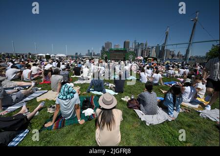 New York, Stati Uniti. 10th luglio 2022. Da una sezione del Pier 6 nel Brooklyn Bridge Park chiamata "The Hill, gli appassionati di tennis guardano dal vivo su un grande schermo mentre il Novak Djokovic della Serbia gioca contro Nick Kyrgios in Australia nella finale maschile di Wimbledon New York, NY, 10 luglio 2022. (Foto di Anthony Behar/Sipa USA) Credit: Sipa USA/Alamy Live News Foto Stock