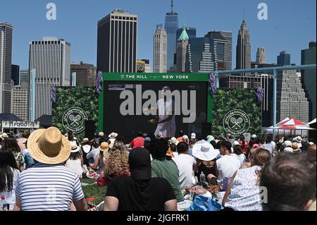 New York, Stati Uniti. 10th luglio 2022. Da una sezione del Pier 6 nel Brooklyn Bridge Park chiamata "The Hill, gli appassionati di tennis guardano dal vivo su un grande schermo mentre il Novak Djokovic della Serbia gioca contro Nick Kyrgios in Australia nella finale maschile di Wimbledon New York, NY, 10 luglio 2022. (Foto di Anthony Behar/Sipa USA) Credit: Sipa USA/Alamy Live News Foto Stock