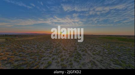 Tramonto del deserto che mostra l'intera di una piccola città agricola Foto Stock