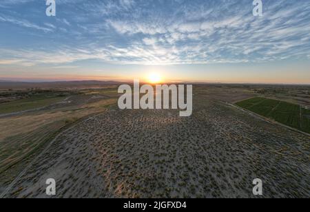 Tramonto del deserto che mostra l'intera di una piccola città agricola Foto Stock