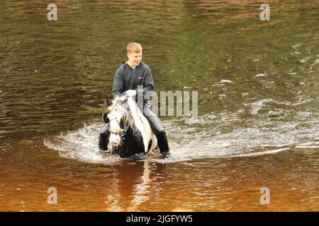 Un ragazzo adolescente che cavalcava il suo cavallo nel fiume Eden, Appleby Horse Fair, Appleby a Westmorland, Cumbria Foto Stock