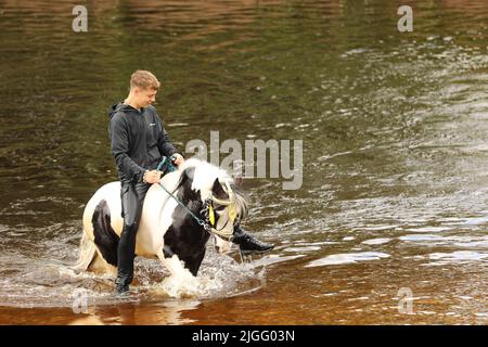 Un ragazzo adolescente che cavalcava il suo cavallo nel fiume Eden, Appleby Horse Fair, Appleby a Westmorland, Cumbria Foto Stock