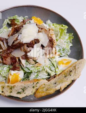 tradizionale insalata caesar con pollo, pancetta, formaggio e lattuga in una ciotola da portata Foto Stock