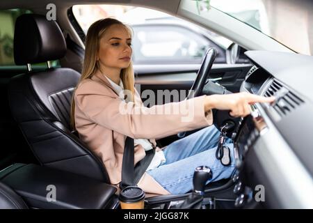 Donna che preme il pulsante di emergenza sul cruscotto dell'auto Foto Stock