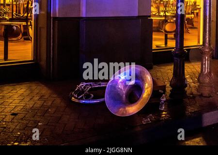 Bourboun Street di New Orleans (Louisiana) di notte, mostrando un trombone lasciato sul terreno da un artista vicino Foto Stock