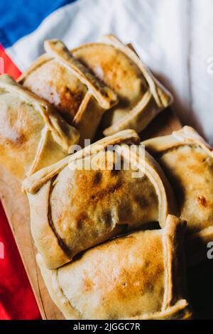 Carne al forno Empanadas cilene sulla bandiera cilena. Concetto di giorno di indipendenza. Messa a fuoco selettiva Foto Stock