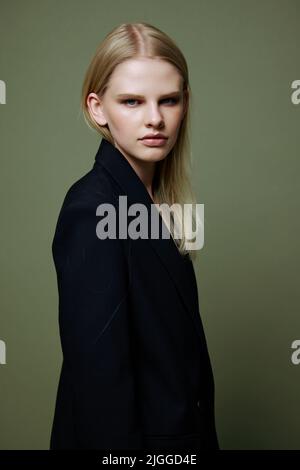 Il giovane modello gira e guarda la fotocamera sopra la spalla. Offerta banner cool. Una ragazza si pone in isolamento in un vestito in uno studio con un verde Foto Stock