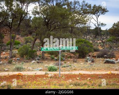 Segnaletica sulla solitaria strada di pietra arenaria Menzies vicino al Lago Ballard, Goldfields, Australia Occidentale Foto Stock