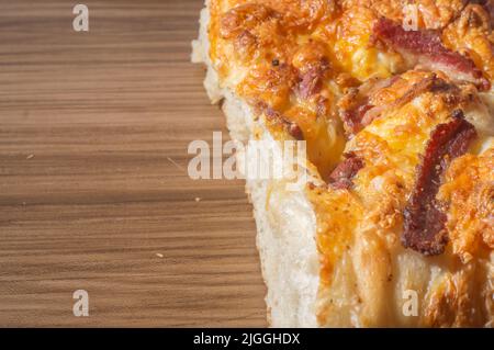 Focaccia italiana appena sfornata con formaggio giallo e pastrami, in tavoletta di legno con spazio per la copia. Foto Stock