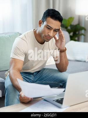Quest'anno volevo davvero ottenere quella casa: Un bel giovane seduto da solo nel suo soggiorno e si sentiva stressato nel calcolo delle sue finanze Foto Stock