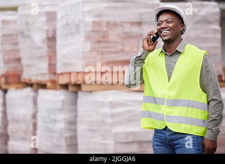 Ha girato il chiamante sul posto. Un giovane e bello lavoratore di costruzione che fa una telefonata mentre si trova in un cantiere. Foto Stock