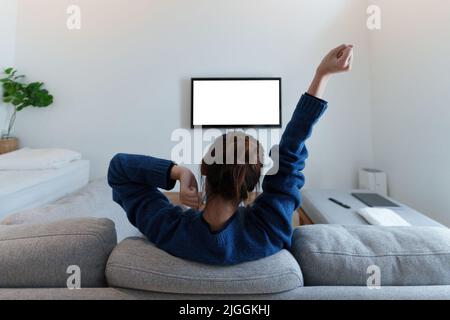 Una donna moderna, entusiasta, guarda la partita di calcio della coppa del mondo, il campionato sul divano a casa. Sport, TV, divertirsi. Foto Stock
