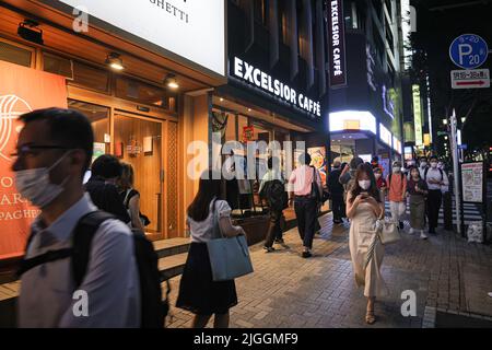 Tokyo, Giappone. 30th giugno 2022. I pedoni che indossano le maschere facciali camminano lungo la strada vicino alla stazione di Shibuya durante il tramonto. Il 30 giugno 2022 il ministro giapponese della Sanità, del lavoro e del benessere Shigeyuki Goto ha annunciato la posizione rivista del governo sull'uso della maschera: 'Anche se si passa da altre persone all'aperto, come quando si cammina per lavorare, non è necessario indossare una maschera per il viso finché non c'è poco o nessuna conversazione.''. Fondamentalmente dire che indossare una maschera al di fuori non è più consigliato. (Credit Image: © Stanislav Kogiku/SOPA Images via ZUMA Press Wire) Foto Stock