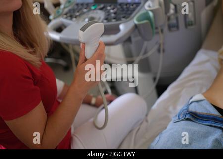 Medico che tiene il trasduttore a ultrasuoni e fa lo screening del paziente Foto Stock