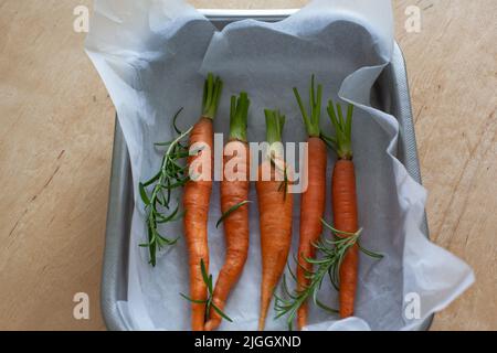 Carota intera giovane con verdure in teglia da forno Foto Stock