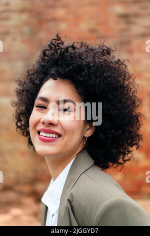 ritratto di una giovane donna con capelli ricci sorridenti Foto Stock