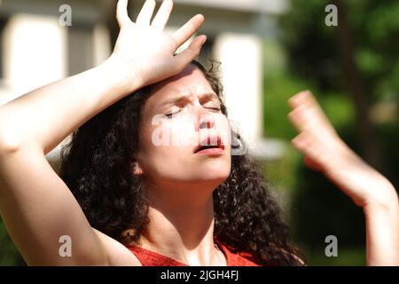 Donna sopraffatta che soffre colpo di calore una giornata di sole in un parco Foto Stock