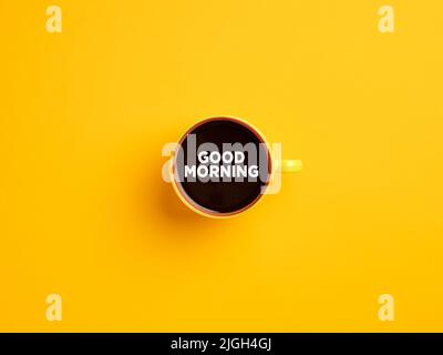 Tazza di caffè gialla con il messaggio Buongiorno su sfondo giallo. Caffè del mattino. Foto Stock