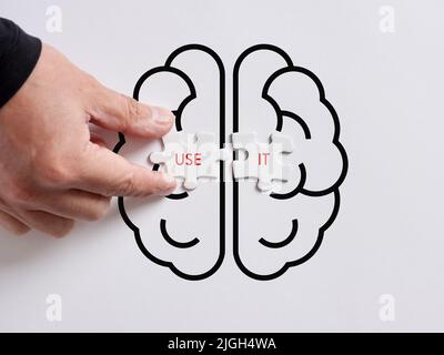 La mano collega i puzzle con le parole usarli su un simbolo umano del cervello. USA il tuo concetto di cervello. Foto Stock