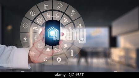 Man Hand show smartphone smart home GUI controlla ogni stanza della casa. Utilizzare l'assistente di automazione domestica intelligente con schermo intelligente su uno schermo virtuale e un Foto Stock