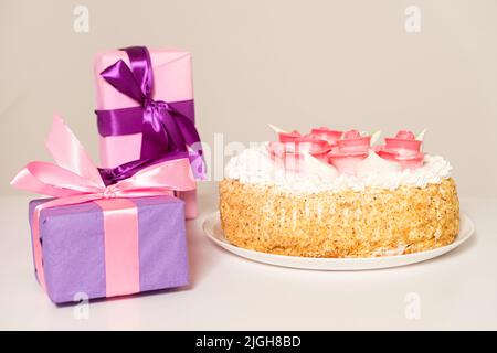 Festa bella torta decorata con fiori di rose sul tavolo su uno sfondo chiaro Foto Stock