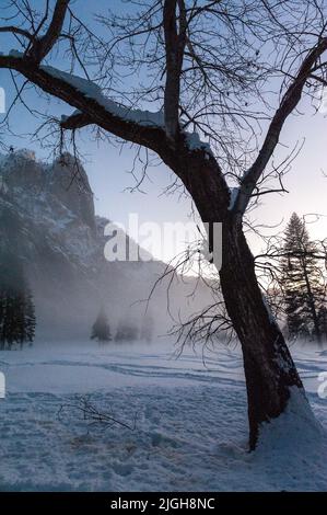 La valle di Yosemite è circondata da un sottile strato di nebbia che si estende sul fiume merced, fornendo un'atmosfera inquietante intorno al tramonto. Foto Stock