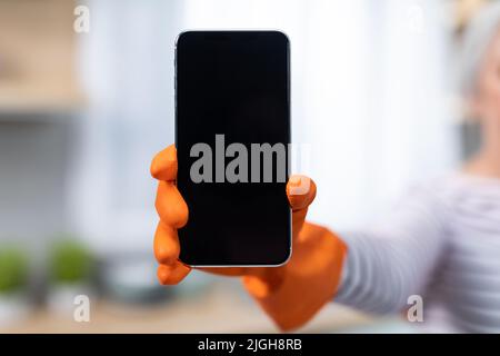 Offerta online. Irriconoscibile Lady indossa un guanto in gomma che tiene grande smartphone vuoto Foto Stock