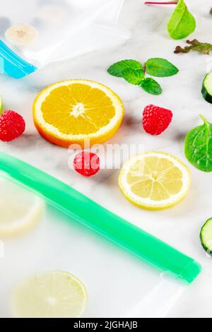 Sacchetti per la conservazione degli alimenti con frutta fresca estiva e verdure, sparati dall'alto su un tavolo da cucina in marmo bianco. Insalata estiva in contenitori con chiusura a zip Foto Stock