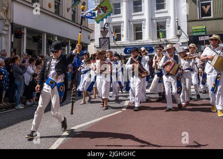 Tom White guida la band dei Golowan attraverso Penzance nelle colorate processioni Mazey Day in Cornovaglia in Inghilterra nel Regno Unito. Foto Stock