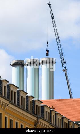 11 luglio 2022, Sassonia, Dresda: Gli esperti vengono sollevati in gondola su una gru sui camini alti 80 metri della centrale termica combinata Nossener Brücke per essere sollevati all'interno dei camini. SachsenEnergie sta togliendo dalla rete la centrale termica e la centrale elettrica per i lavori di ristrutturazione previsti. Il completamento della ristrutturazione è previsto per il 18 luglio 2022 e lo stabilimento CHP deve essere ricollegato alla rete. Il nuovo HKW è stato costruito tra il 1993 e il 1995. Tre turbine a gas e una turbina a vapore generano elettricità e calore nell'impianto accoppiato nel processo di cogenerazione. Questi possono essere opera Foto Stock